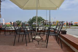 un grupo de sillas y una sombrilla en una cubierta en Korali Hotel, en Paralia Katerinis