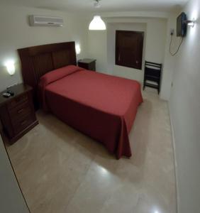 a bedroom with a red bed and a television at Veracruz in Granada