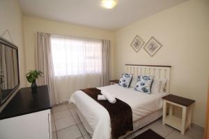 a bedroom with a bed with blue pillows and a window at Michael Point 6 in Shelly Beach