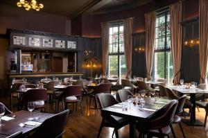ein Restaurant mit Tischen, Stühlen und Fenstern in der Unterkunft Elmbank York, Tapestry Collection by Hilton in York