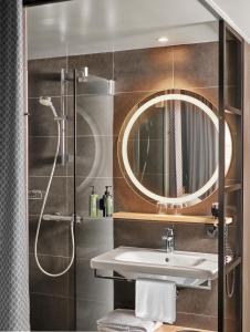 a bathroom with a sink and a shower with a mirror at H2 Hotel Saarbrücken, Trademark by Wyndham in Saarbrücken +30 photos