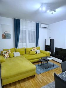 a living room with a yellow couch and a tv at Pleasure Lux1 Apartment in Belgrade