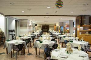 una sala da pranzo con tavoli e sedie con tovaglie bianche di Hotel Faro a Montichiari