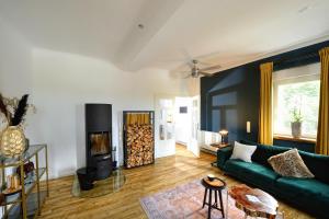 - un salon avec un canapé vert et une cheminée dans l'établissement Chalet-Apartement in ehemaliger Hofraite, à Bruchköbel