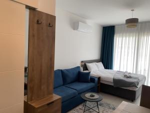 a living room with a blue couch and a bed at Deja Blue, block S4, unit 26 in Kalogrea