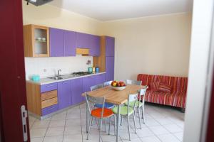 a kitchen with purple cabinets and a table and chairs at Residence Soleluna in Praia a Mare