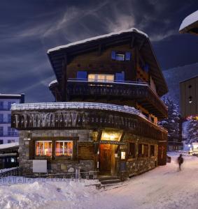 una cabaña de madera en la nieve frente a un edificio en Guesthouse by the rex, en Zermatt