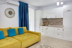 a living room with a yellow couch and a kitchen at Apartament Atlantis by ALZ in Mamaia Nord