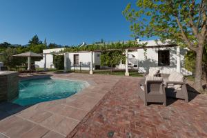 a patio with chairs and a pool in front of a house at La Galiniere Guest Cottages in Franschhoek