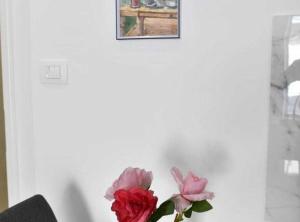 a vase with two roses and a picture on a wall at Charming Sinj Town Studio Apartments in Sinj