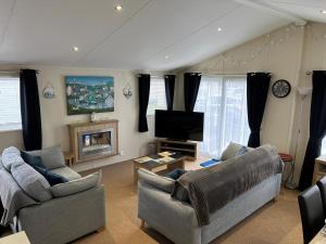 a living room with two couches and a television at Stunning Lodge Boasting Large Decking Area At California Cliffs Ref 50008L in Great Yarmouth