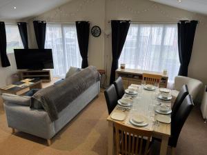 a living room with a table and a couch at Stunning Lodge Boasting Large Decking Area At California Cliffs Ref 50008L in Great Yarmouth