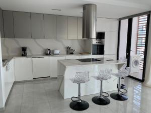 a kitchen with white cabinets and bar stools in it at Apartamento Deluxe Santa Filomena in Mindelo