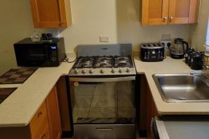 a kitchen with a stove and a sink at 2-Bed Sleeps 4 Private Garden Parking in Portmore
