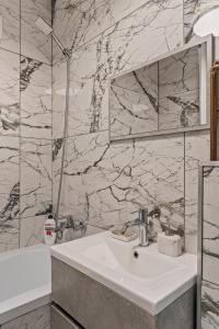 a bathroom with a sink and a tub and a mirror at Garsoniera LUX Piata Natiunile Unite in Bucharest