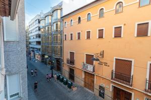 a group of people walking down a street between buildings at La petite maison de Nadette 2 in Gandía