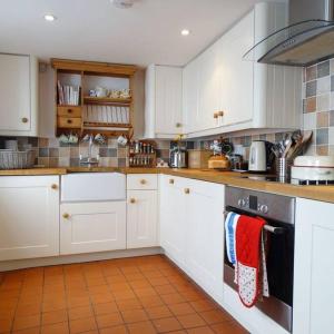 a kitchen with white cabinets and a stove top oven at Stunning Town house with parking, fire, games room in Topsham