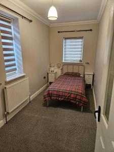 a bedroom with a bed and two windows at Large Bungalow to sleep up to 8 in Slough