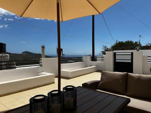 a patio with a couch and an umbrella on a roof at Nick & Alex, Beautiful Village Apartment in Míthoi