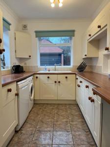 a large kitchen with white cabinets and a window at West Street House-Furnished Let in Hoyland Nether
