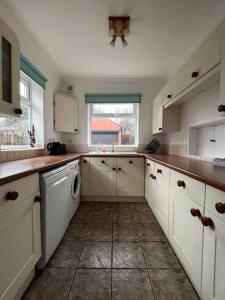 a large kitchen with white cabinets and a window at West Street House-Furnished Let in Hoyland Nether +8 photos