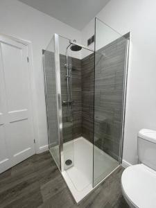 a glass shower in a bathroom with a toilet at West Street House-Furnished Let in Hoyland Nether