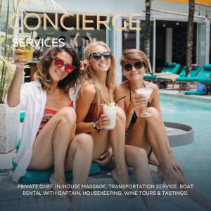 three women sitting next to a pool with drinks at Lakeshore Retreat with Concierge Services in Kingsland