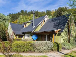 a yellow house with a black roof at Wesley House Hosteria Boutique in San Martín de los Andes