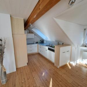an attic kitchen with white cabinets and a staircase at Ferienwohnung Ludwigshöhe in Kempten +11 photos