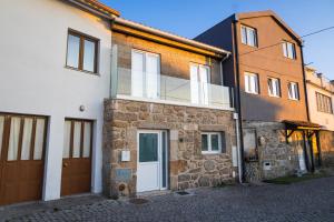 a stone house with a white door and windows at Casinha do Adro in Paços da Serra