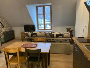 a living room with a table and a couch at Maison La Tourelle in Baume-les-Dames