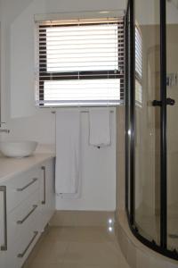 a bathroom with a shower and a window with towels at 4 Kiaat Suites in Klerksdorp +3 photos