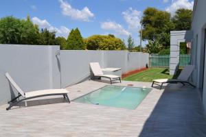 a patio with two chairs and a swimming pool at 4 Kiaat Suites in Klerksdorp