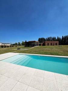 a blue swimming pool in front of a house at Casa de diseño en Chacras de la Trinidad in Cañuelas