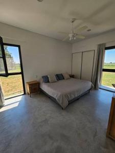 a bedroom with a bed in a room with large windows at Casa de diseño en Chacras de la Trinidad in Cañuelas
