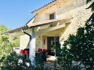 una casa de piedra con sillas rojas delante de ella en Le Domaine de la Ronce - Gîte & Spa, en Cézac