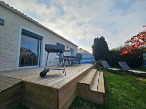 a barbecue grill sitting on a wooden deck at Villa ISKA - 6Velos-Calme-Piscine-Moderne-Centre-Port-Plages in La Tremblade
