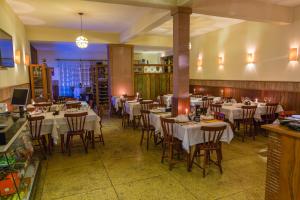a restaurant with white tables and chairs in a room at Hotel Bandeirantes - Unidade Centro in Cachoeira do Campo