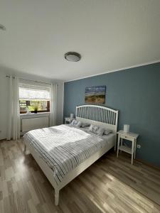 a bedroom with a white bed and a blue wall at Ferienwohnung Kastanienhof in Hasselberg +3 photos