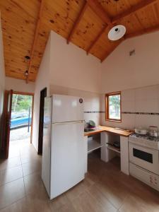 a white refrigerator in a kitchen with wooden ceilings at Los Colibríes in Lago Puelo +4 photos