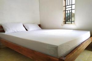 a bed with white sheets and a window in a room at Hotel O Bontotangnga Homestay in Balangberu