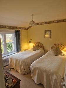 a bedroom with two beds and a window at Stanshope Hall in Alstonfield