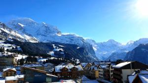 a city with snow covered mountains in the background at Hotel Schönegg in Wengen