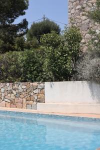a swimming pool with a stone retaining wall next to a stone wall at La Villa in Favone +29 photos
