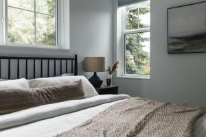a white bedroom with a bed and two windows at Lokis Loft and Cellar at the 1896 Building in Kaslo