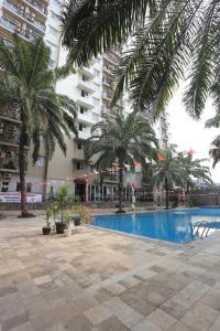 a swimming pool with palm trees and a building at Apartemen Mutiara Bekasi by Alfa Rooms in Pekayon Satu