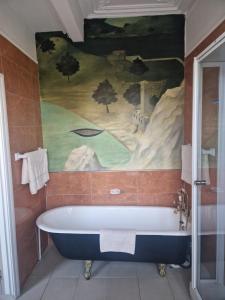 a bath tub in a bathroom with a painting on the wall at Stanshope Hall in Alstonfield