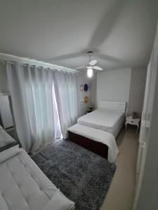 a white bedroom with two beds and a rug at Casa de praia no Peró Cabo Frio com Piscina e Hidromassagem in Cabo Frio +128 photos