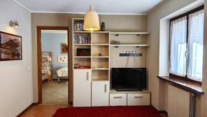 una sala de estar con TV en un estante de libros blanco en Hostdomus - Chalet Sciatori Garden, en Pragelato