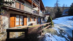 Una casa con puertas de madera y una valla en la nieve. en Hostdomus - Chalet Sciatori Garden, en Pragelato